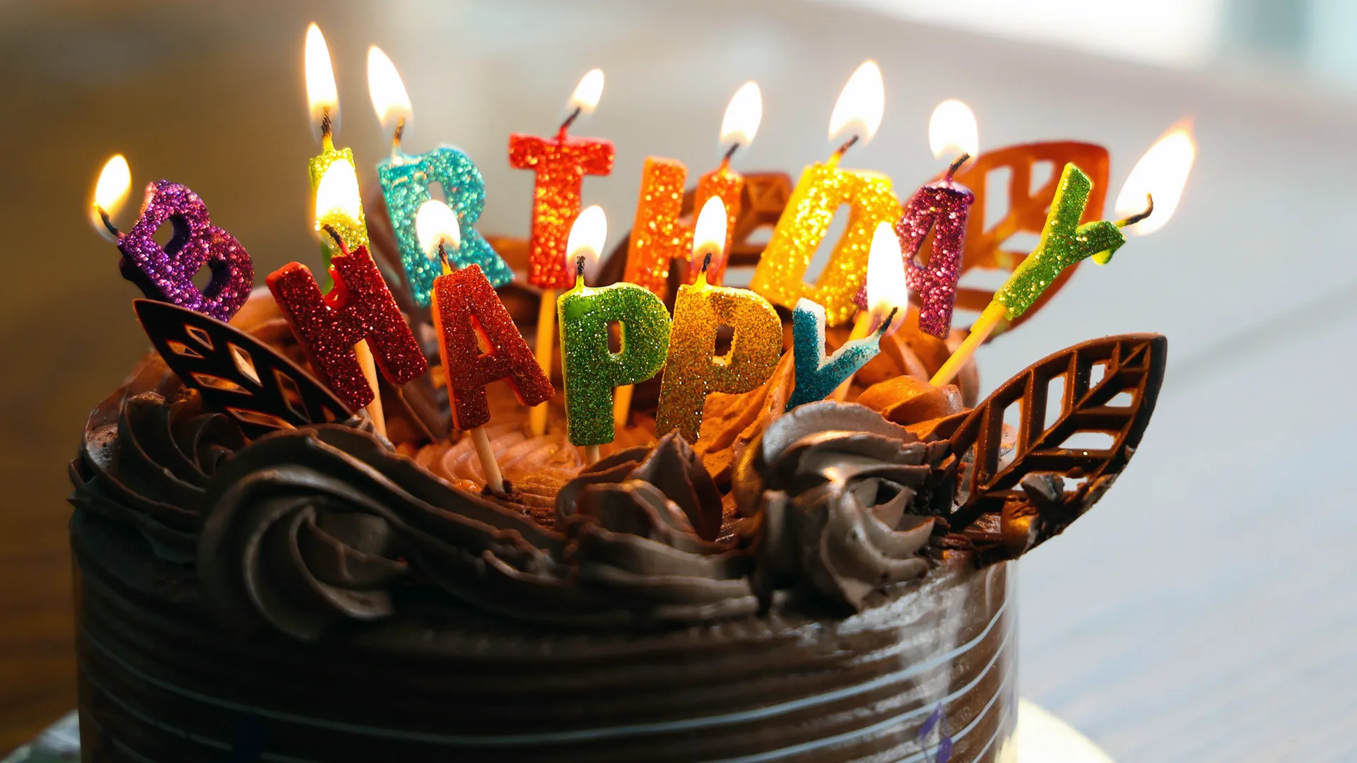 A photograph of a birthday cake with colourful glitter candles