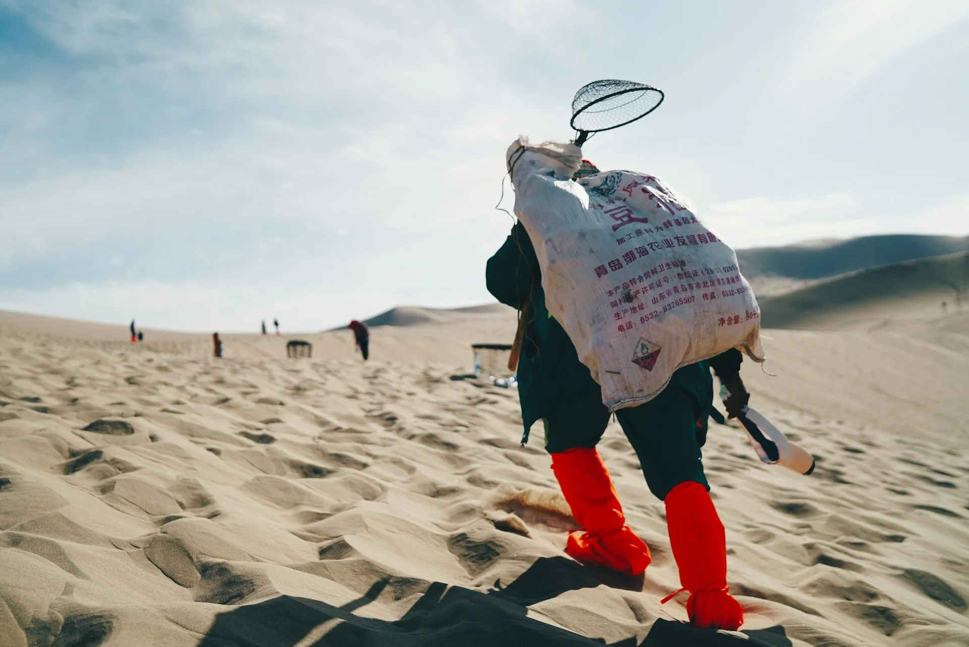 Person carrying sack on sand