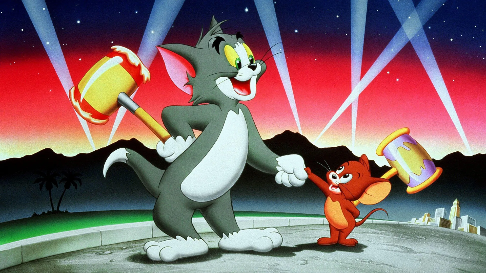 An image from Tom and Jerry showing Tom and Jerry shaking hands whilst holding giant mallets behind their backs. They are stood on a road against a red sky lit by searchlights.