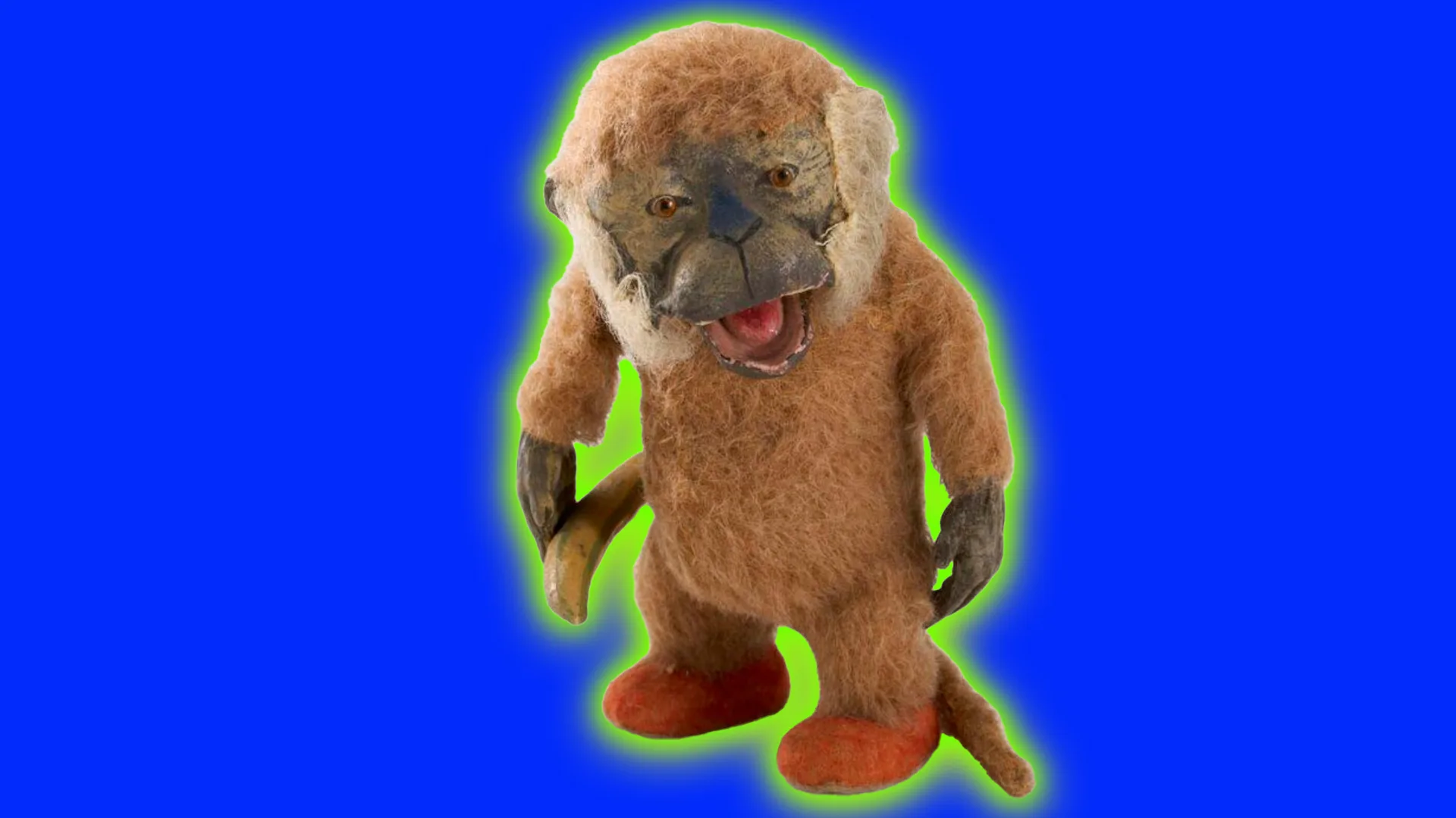 An image of a soft toy monkey stood upright with it's mouth open exposing a pink tongue. It is holding a banana and has little orange feet. It is set against a blue cobalt background with a green halo.