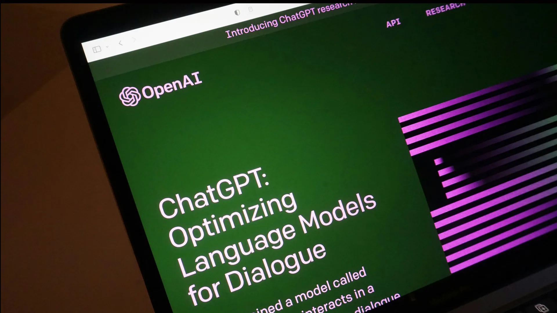 An image of a screen showing the homepage of ChatGPT which says "ChatGPT: Optimizing Language Models for Dialogue" with a green background and purple lines.