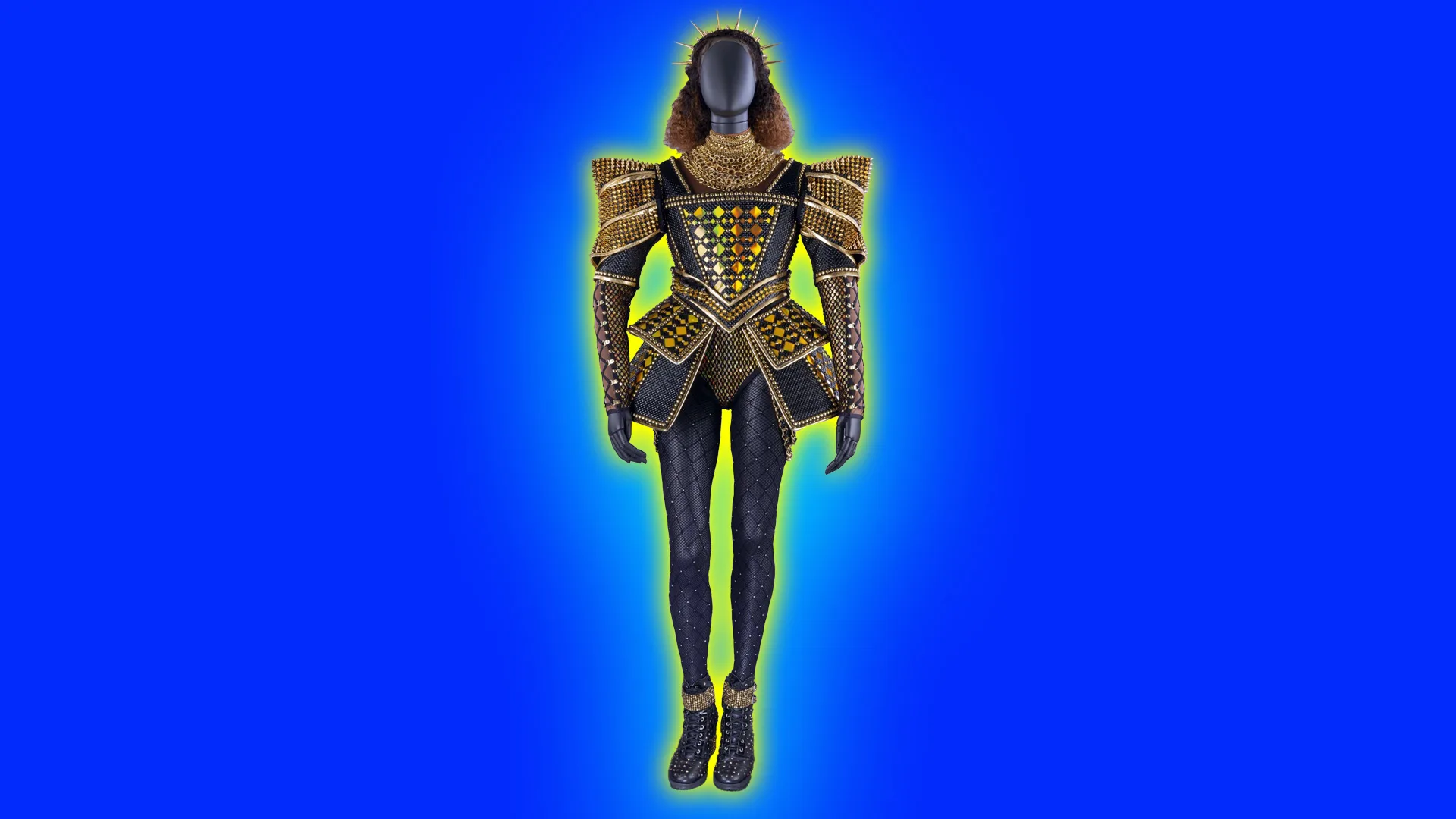 An image of a theatre costume showing a black mannequin wearing a gold and black outfit for the character of Catherine of Aragon in the British musical SIX. It is set against a blue background with a yellow and blue halo.