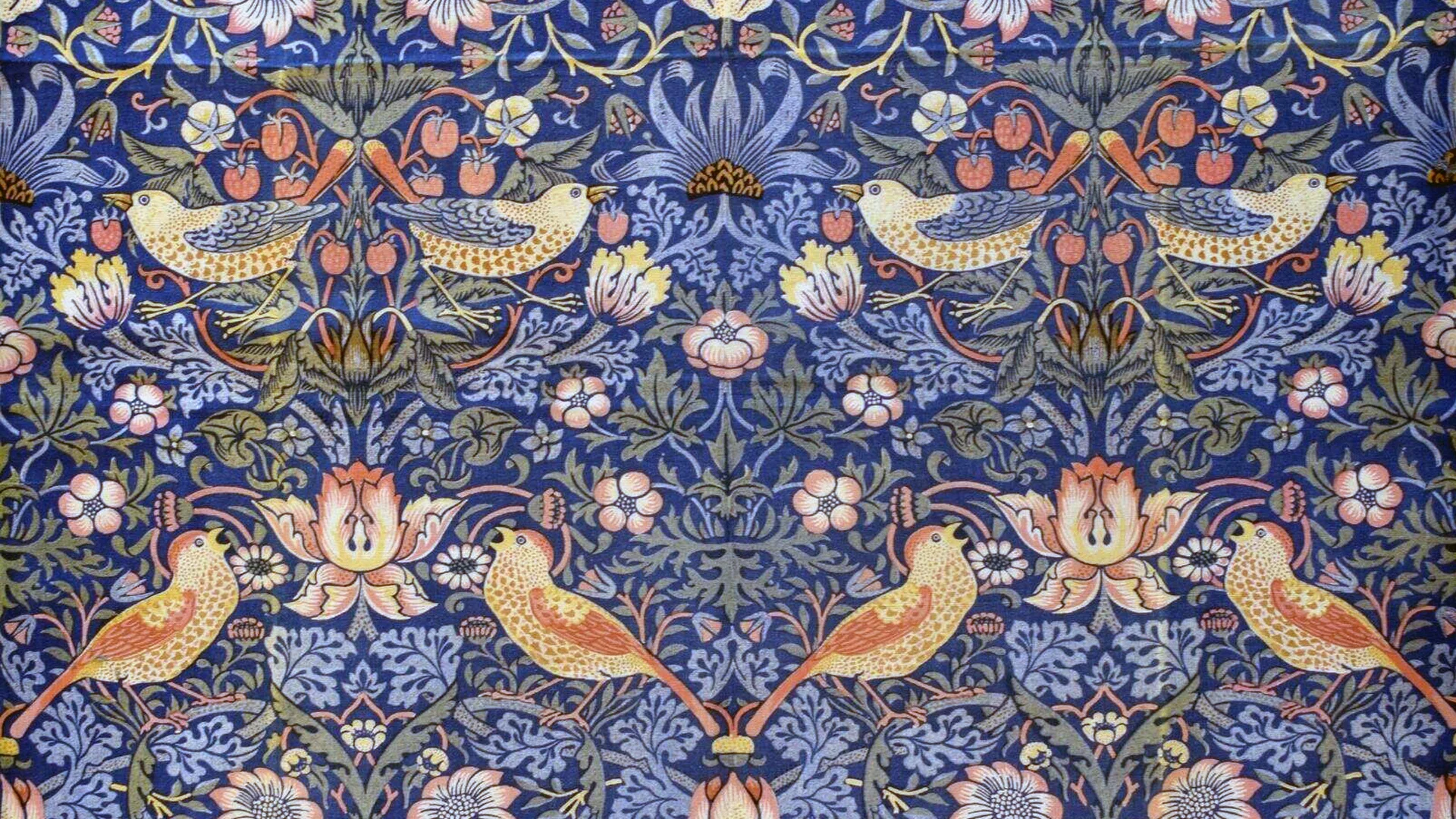 A pattern of William Morris strawberry thief in blue showing symmetrical arrangements of flowers, leaves and birds.
