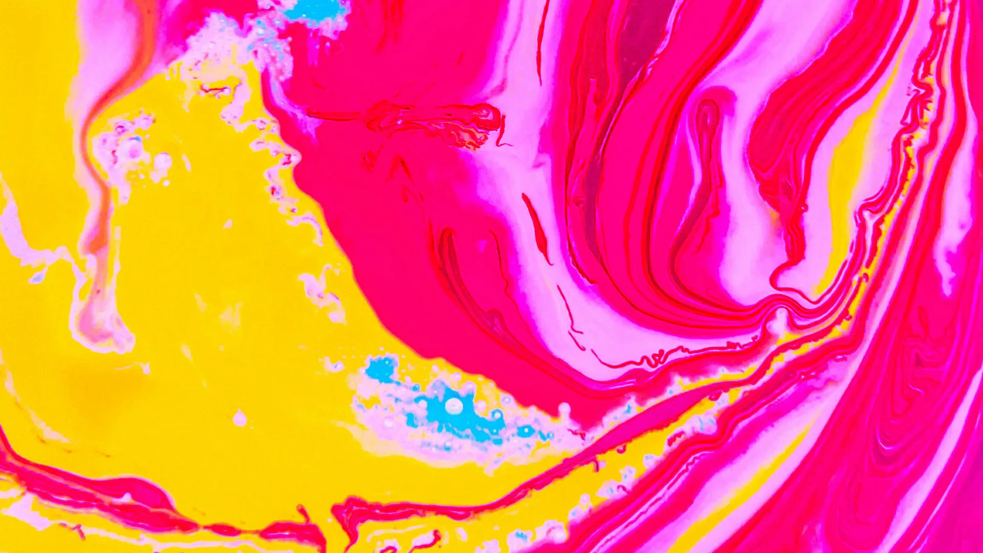 An image of swirling colours of bright pinks and yellows with splashes of blue.