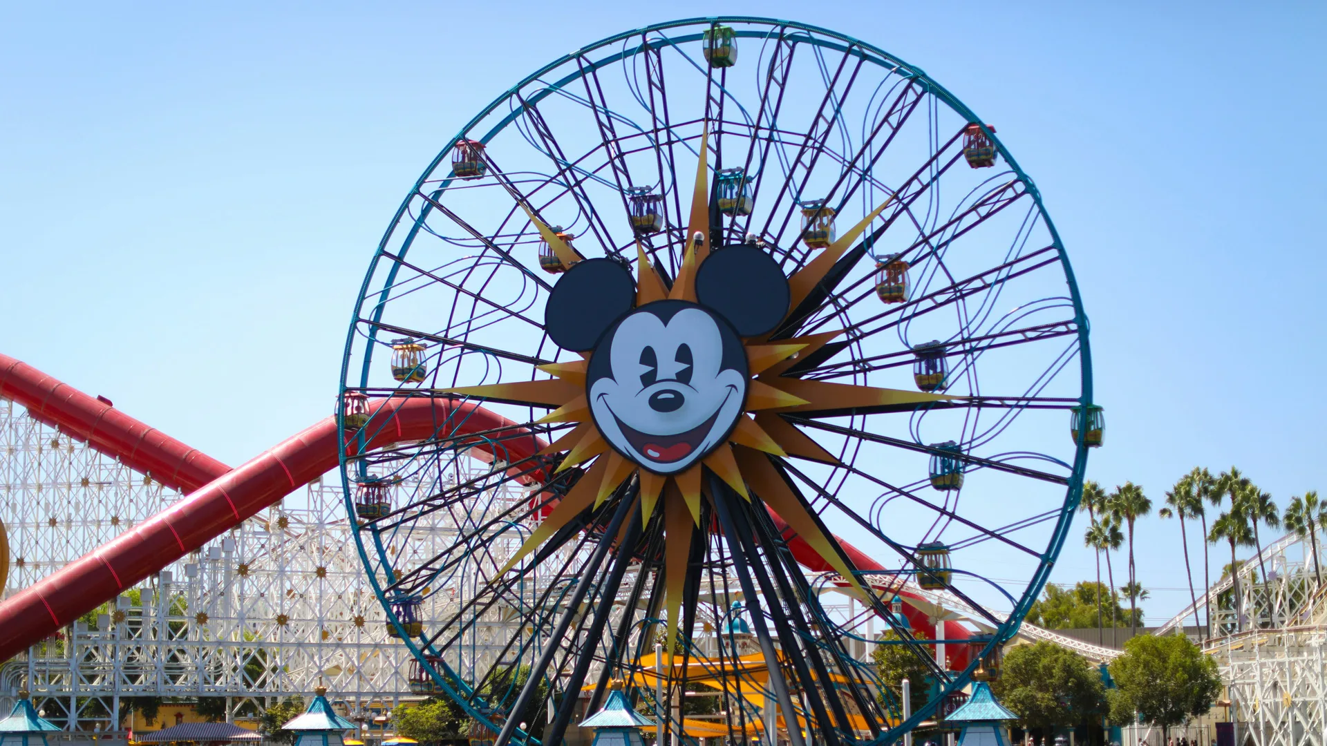 A photo of a Disney parks ferris wheel with Mickey Mouse in the centre against a blue sky.