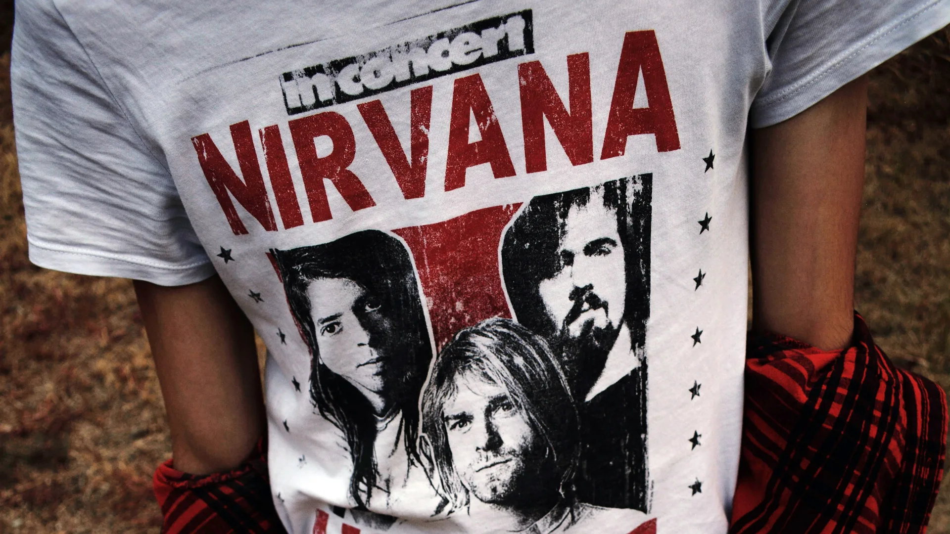 A photo of a tshirt with NIRVANA on the front in red letters and a picture of the band.