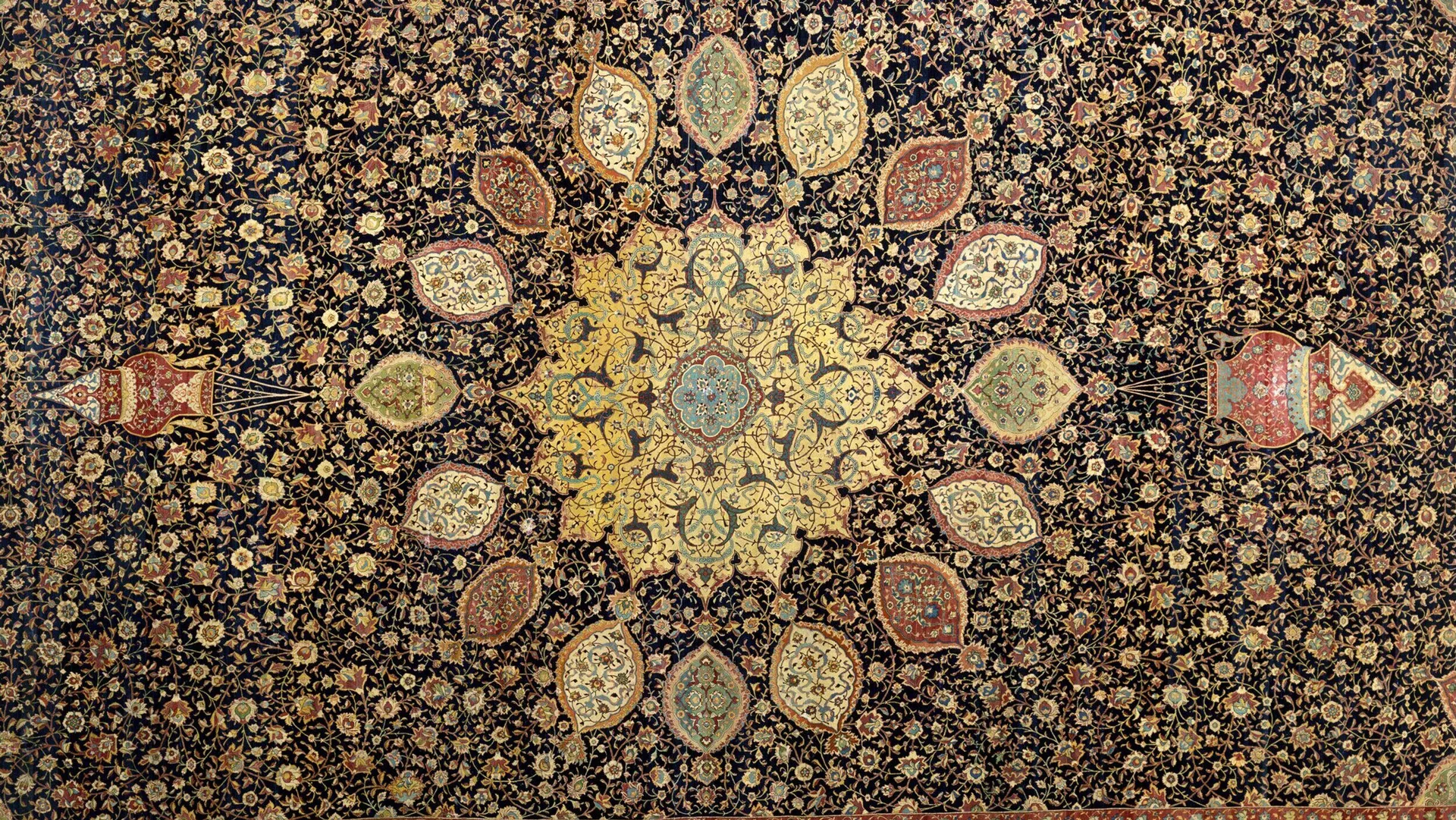 A photo of a carpet with a circular pattern in the centre and two hanging lamps either side in colours of golds, browns, creams and reds.