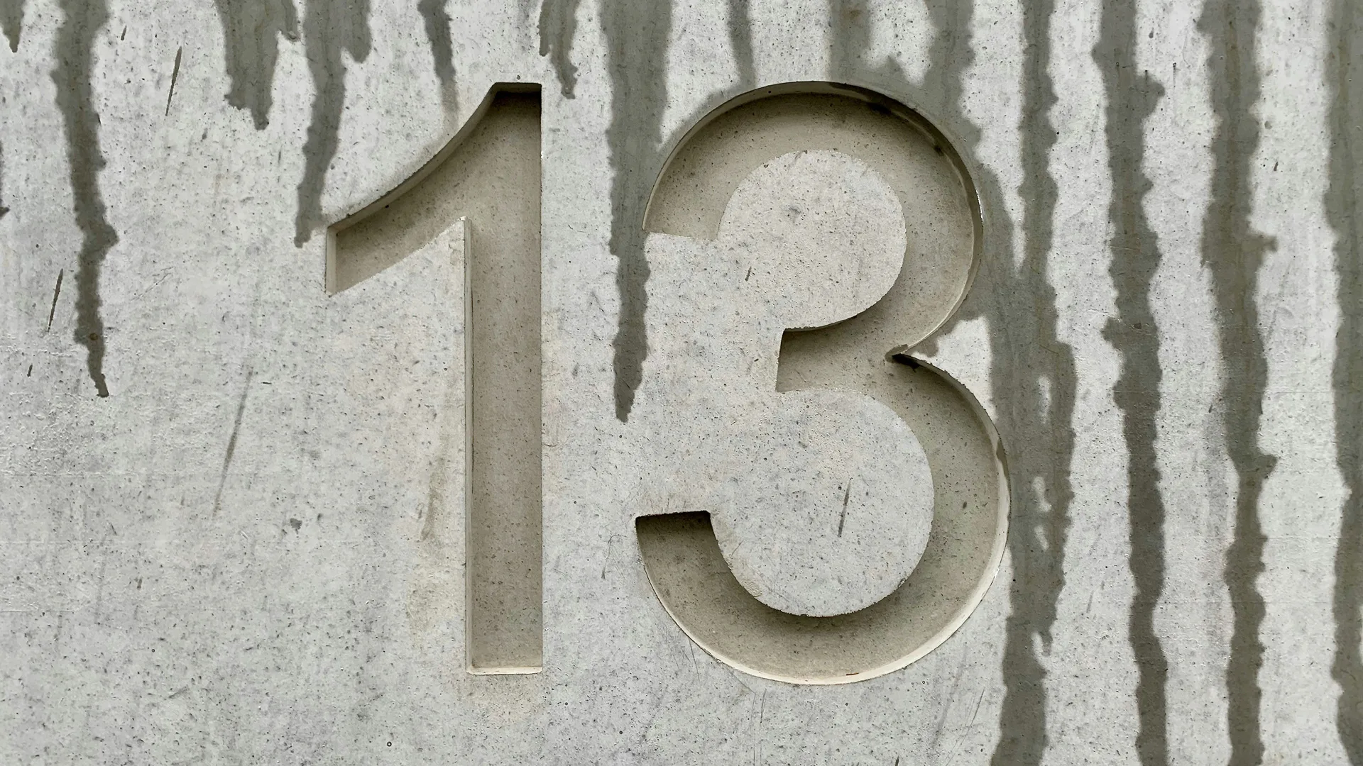 An image of a number 13 engraved in a wall with water drips coming down