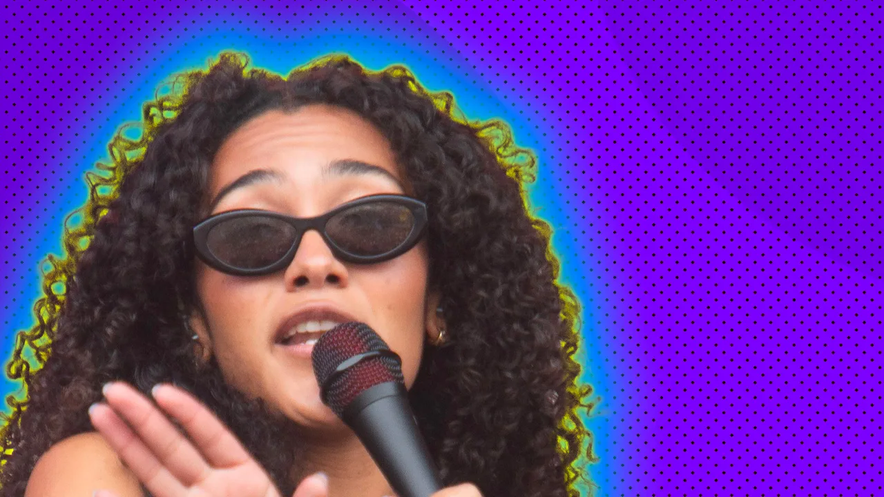 A photo of singer Olivia Dean singing into a microphone wearing sunglasses and holding her hand near the mic, set against a purple background with yellow and blue halo.
