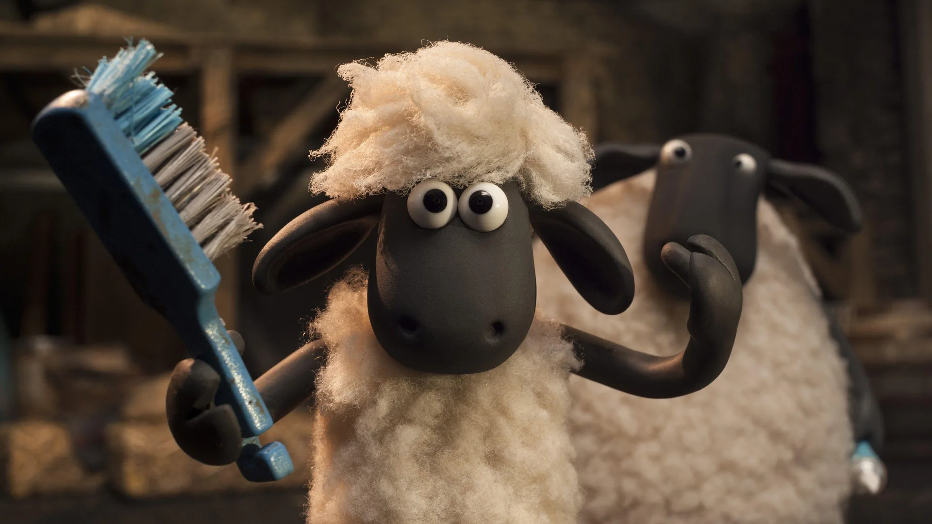 A still from Shaun the Sheep movie showing Shaun waving at the viewer holding a giant blue toothbrush with another sheep behind him looking on in a barn setting.