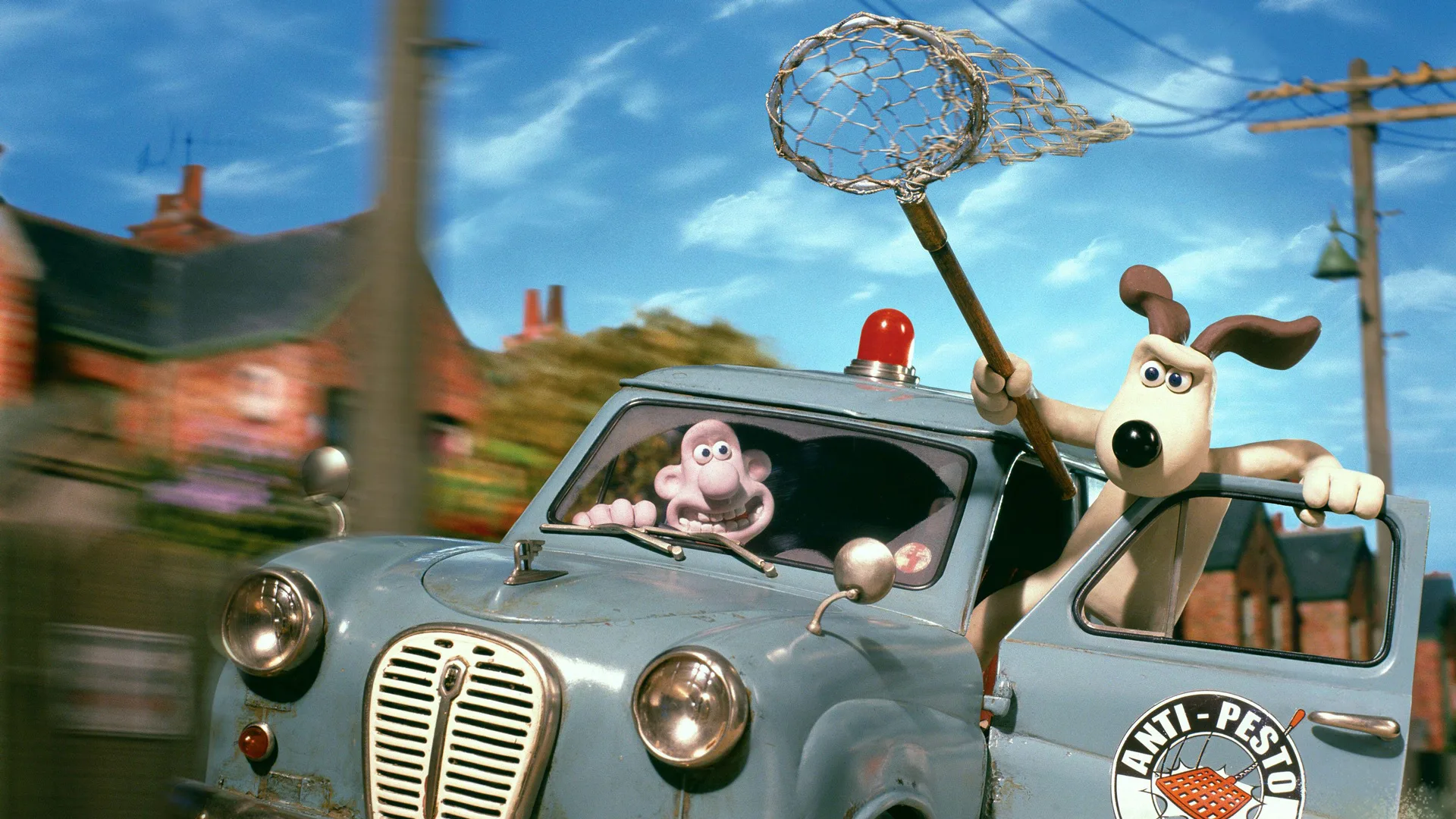 A still from Wallace and Gromit The Curse of the Were-Rabbit showing Wallace and Gromit driving a car with Gromit hanging out holding a giant net against a blue sky and street.