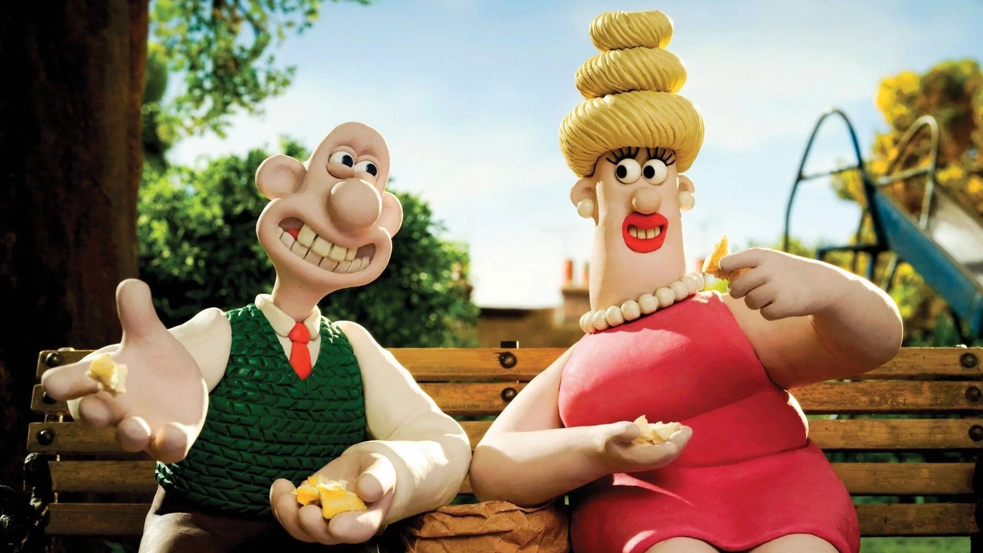 A still from A Matter of Loaf and Death showing Wallace sat next to a blonde lady on a bench sharing a snack against a leafy background with blue sky and buildings.