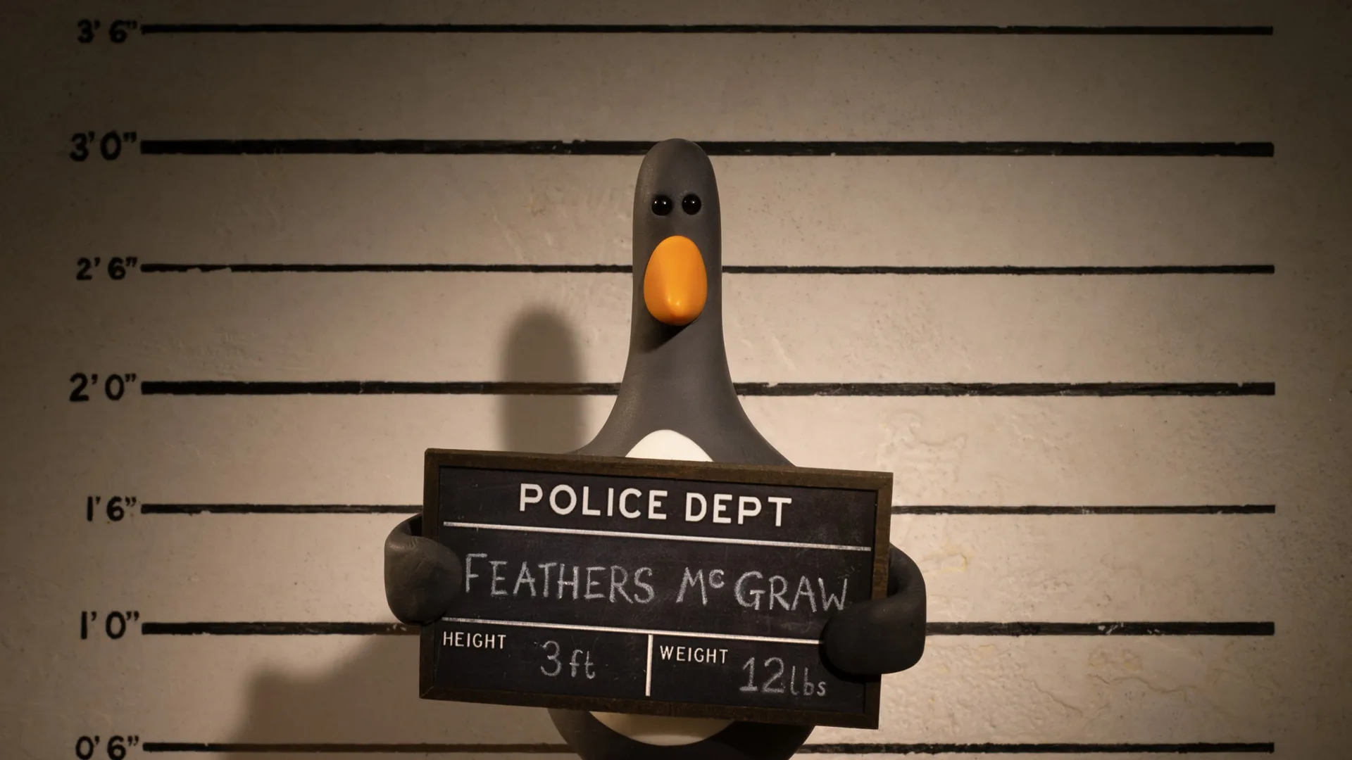 A still from The Wrong Trousers showing Feathers McGraw holding a police sign against a line-up background.