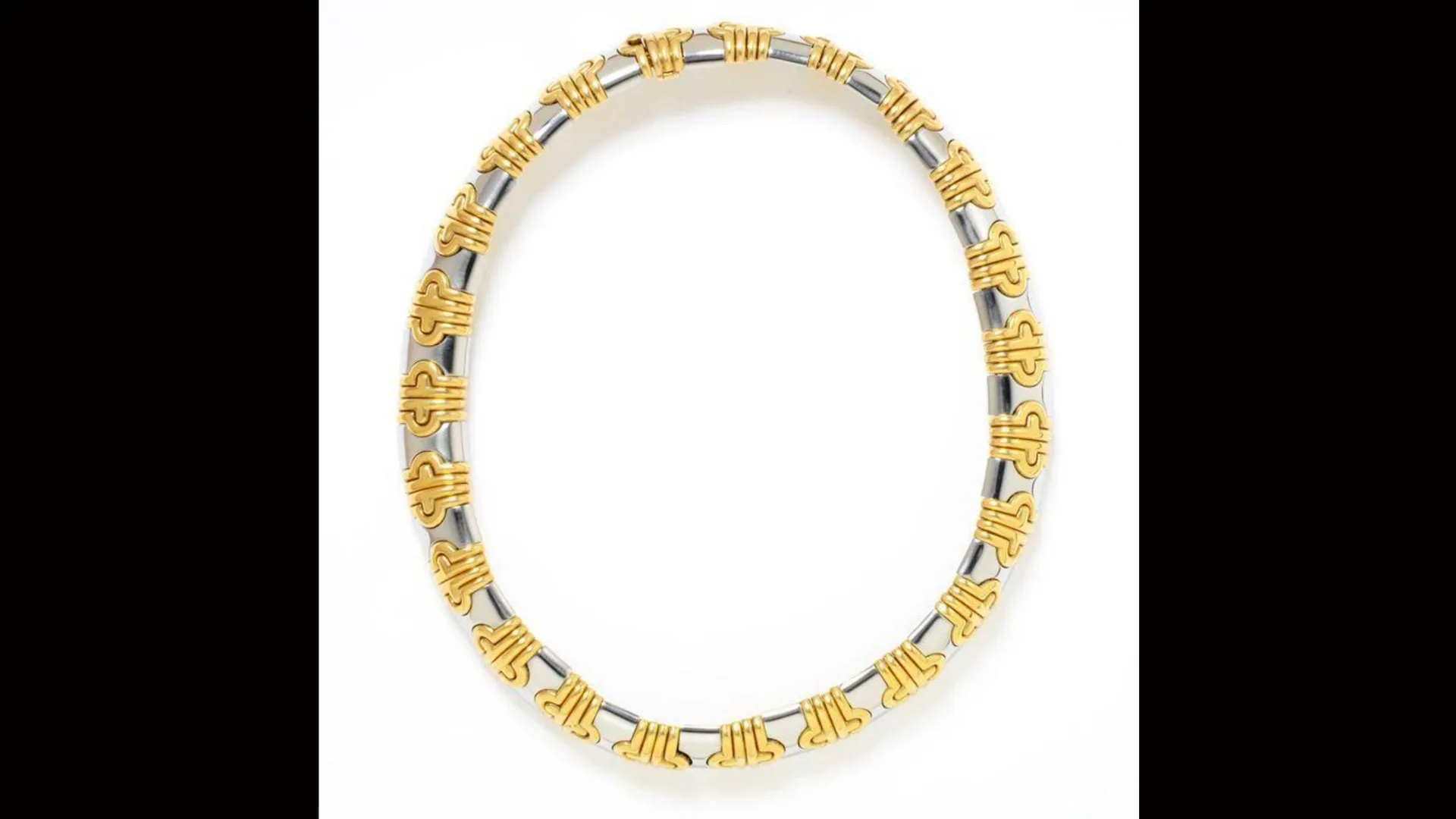 A photo of a gold necklace by Bulgari with interlocking symbols in gold and silver chain.