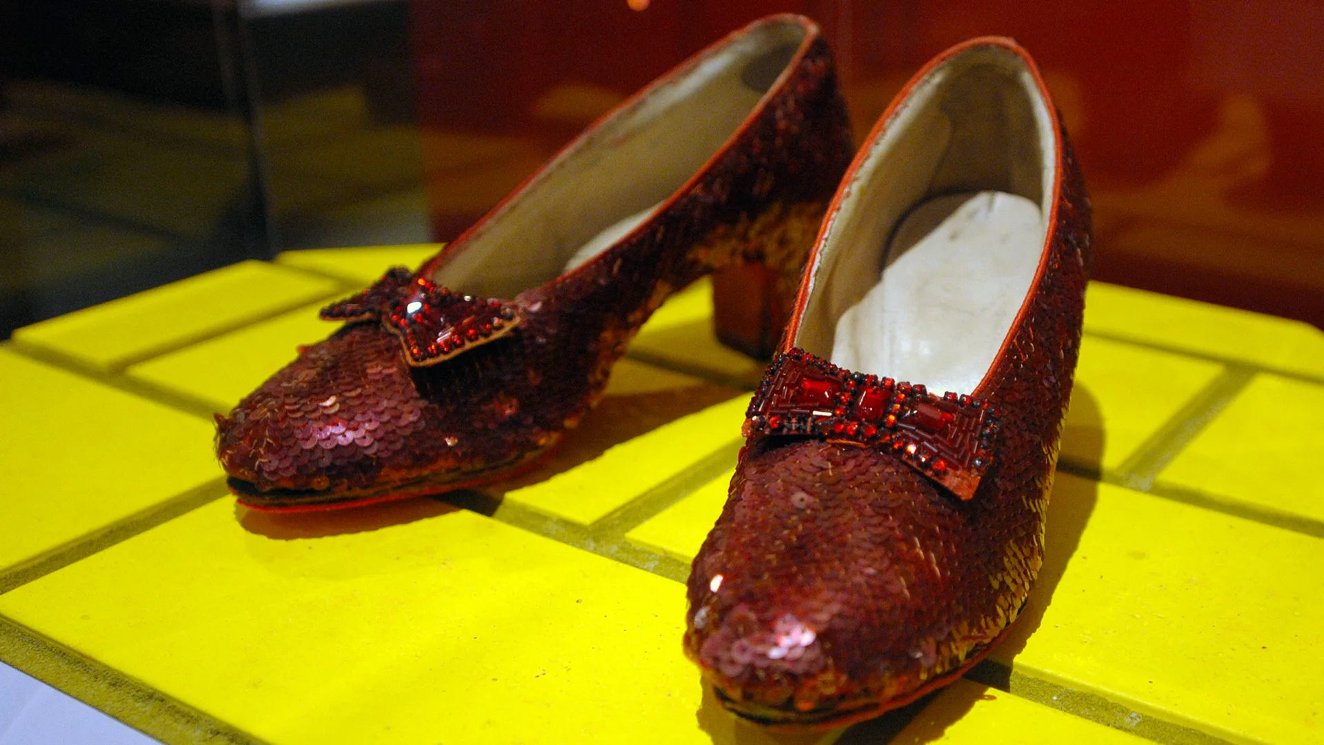 A photo of the Ruby Red Slippers from The Wizard of Oz. They are displayed on a yellow brick road flooring.
