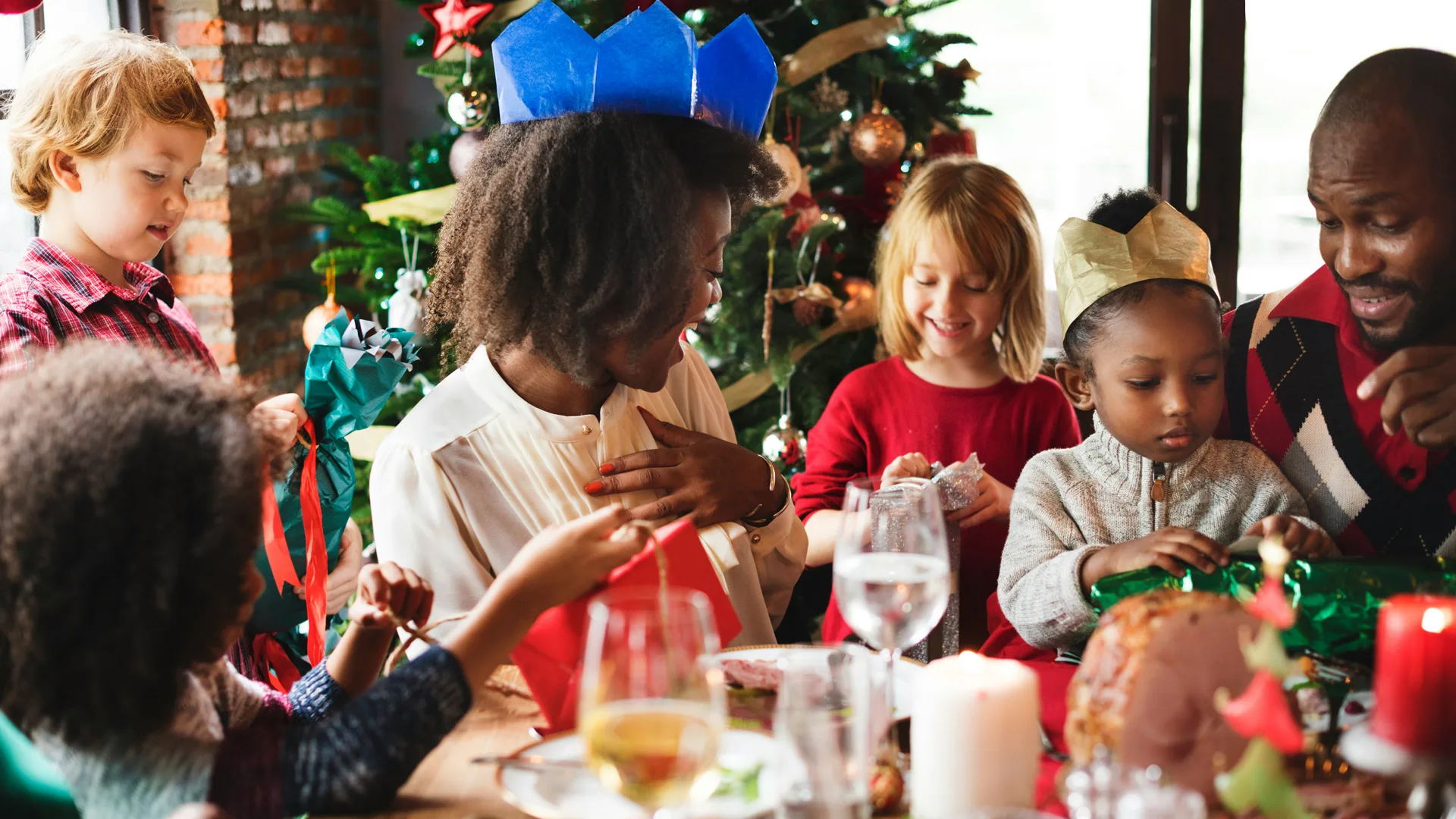 A photo of a family enjoying Christmas dinner with a Christmas tree behind them.