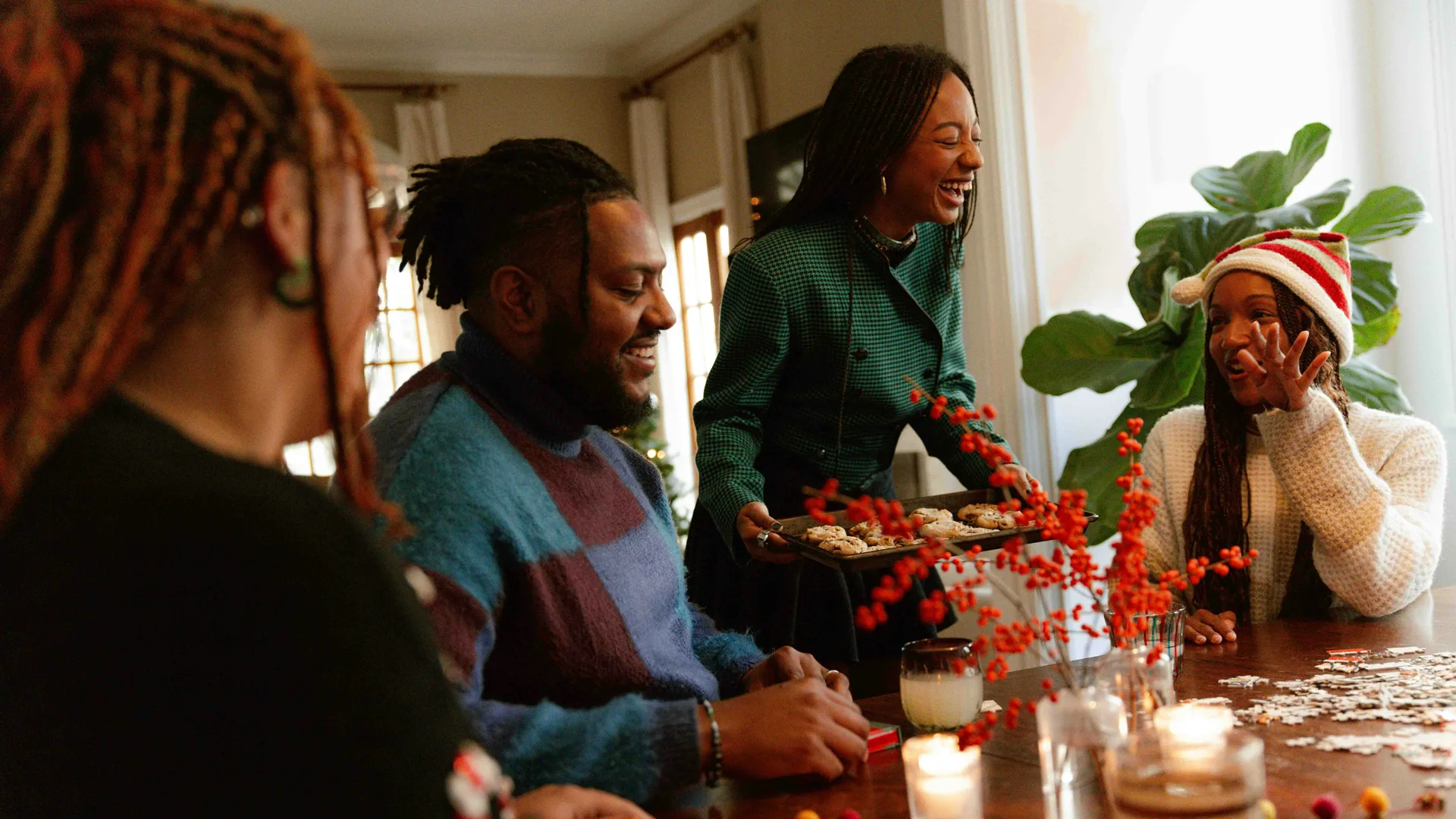 A photo of a family enjoying Christmas activities at the dining table with red berries and candles.