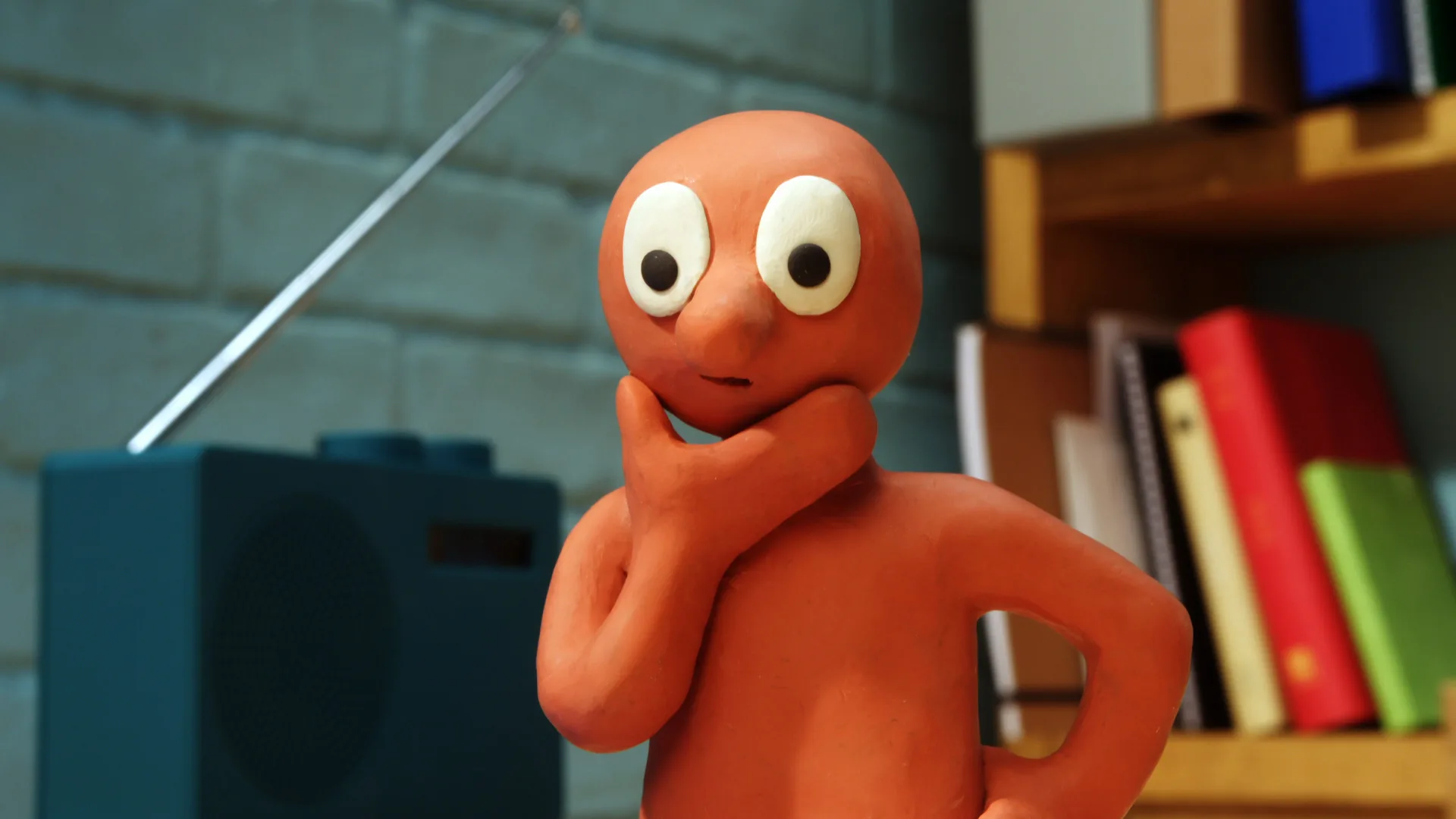 A still from Morph "Bin it to Win it" showing Morph stood with his hand to his chin deep in thought. Behind is a brick wall background and television set.