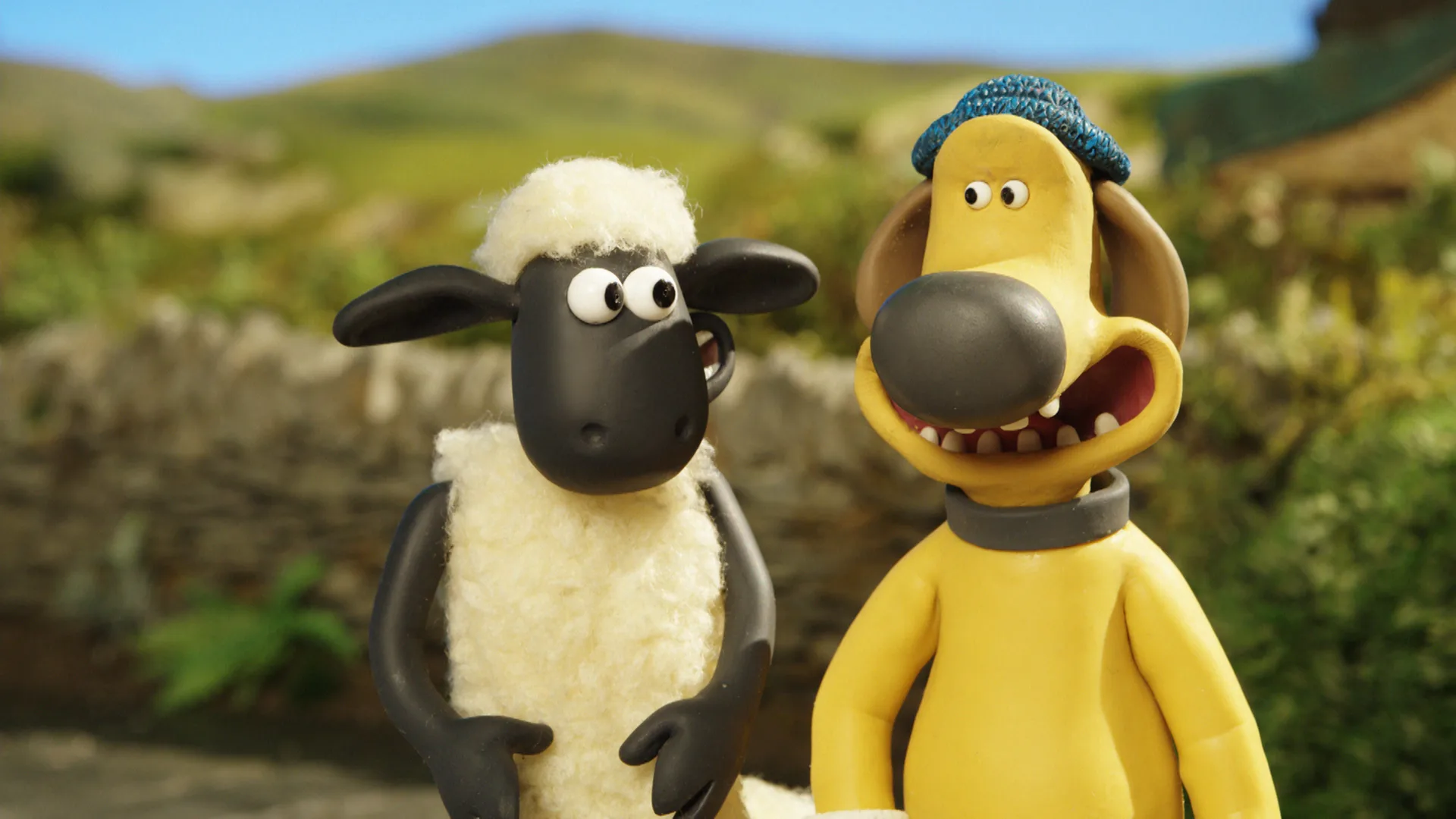 A still from Shaun the Sheep "The Smelly Farmer" showing Shaun and Bitzer stood next to eachother in a field with a stone wall behind them and blue sky above.