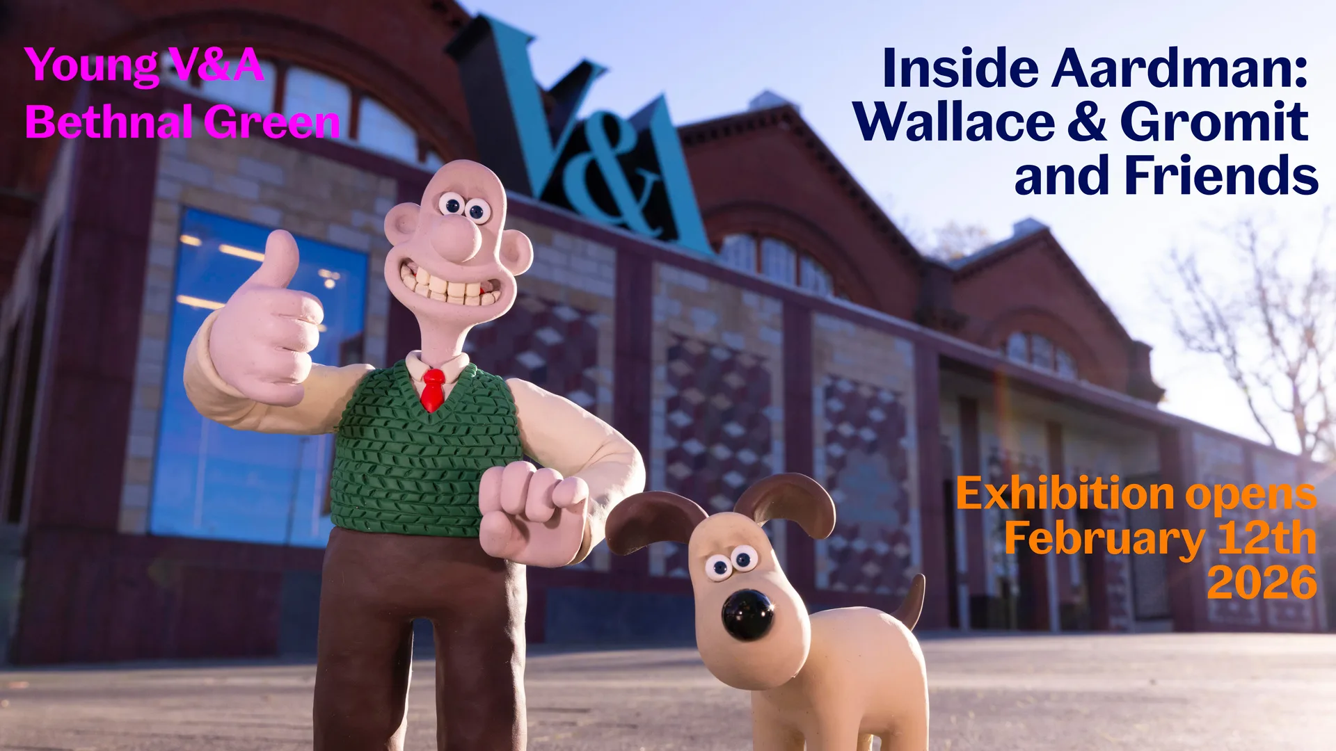 Wallace and Gromit stood outside the Young V&A museum with a clear blue sky above them.