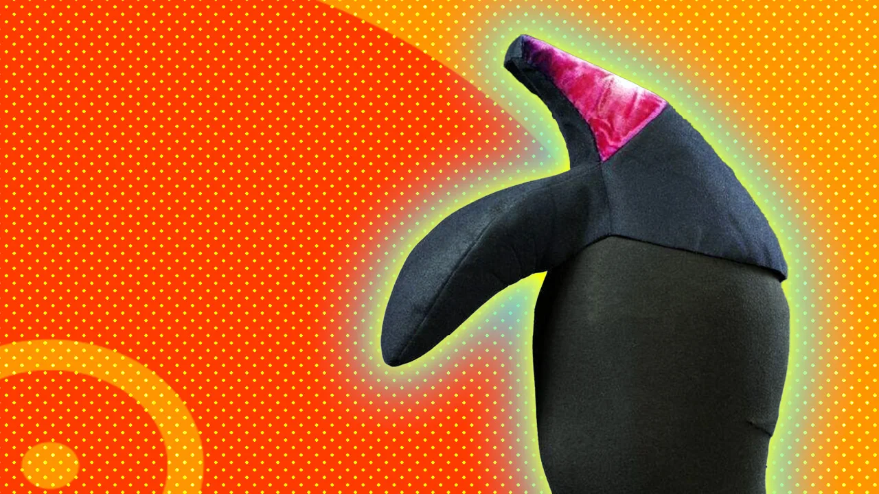 An image of a hat shaped like a shoe upside down on the mannequin's head with a pink heel, designed by Elsa Schiaparelli. It is set against a bright orange background with a blue and yellow halo.