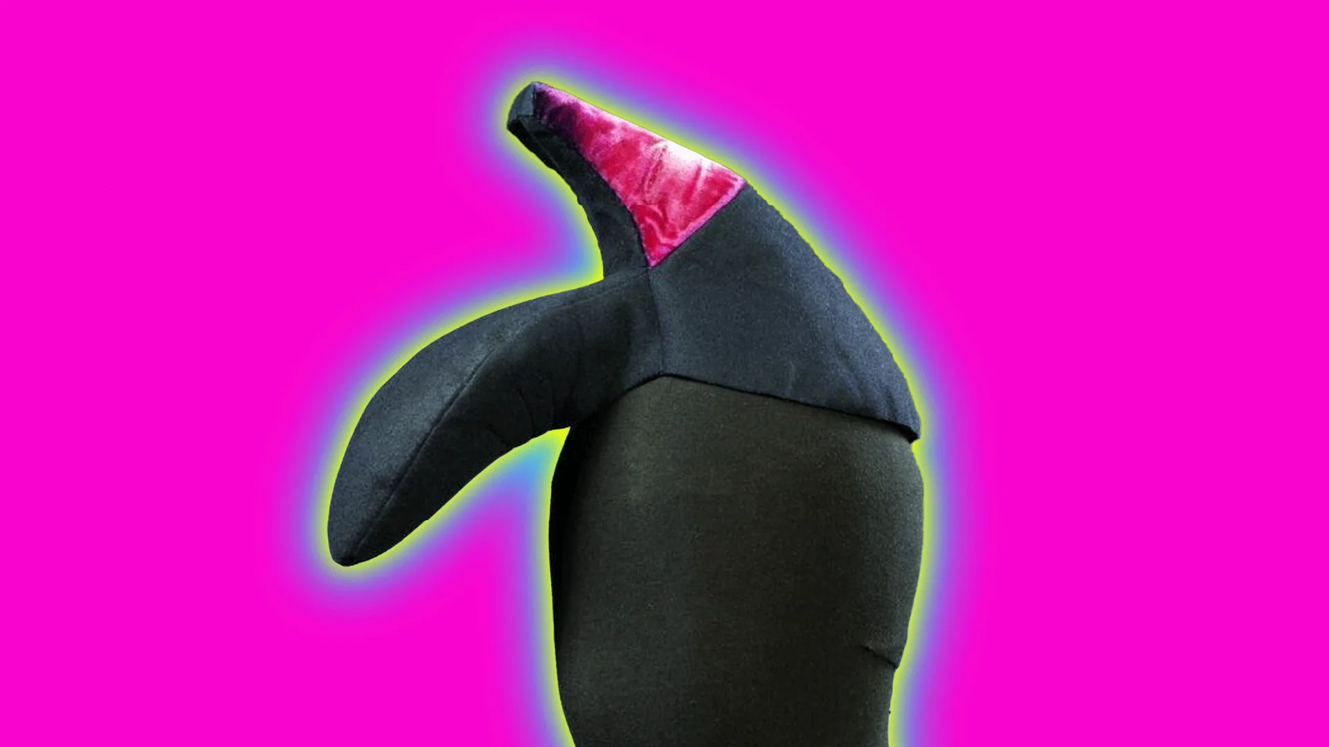 An image of a hat shaped like a shoe upside down on the mannequin's head with a pink heel, designed by Elsa Schiaparelli. It is set against a bright pink background with a blue and yellow halo.