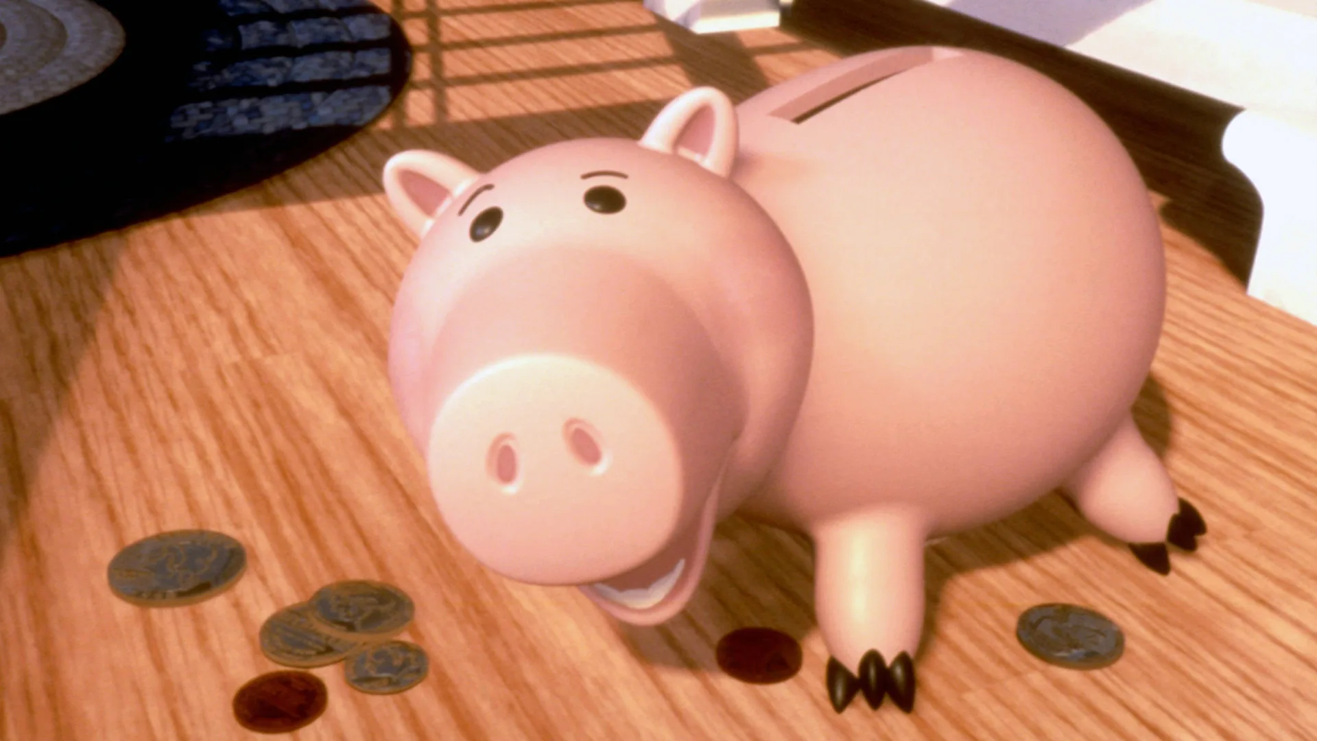 A still from Toy Story showing the pig character looking up surrounded by coins on a wooden table he is stood on.