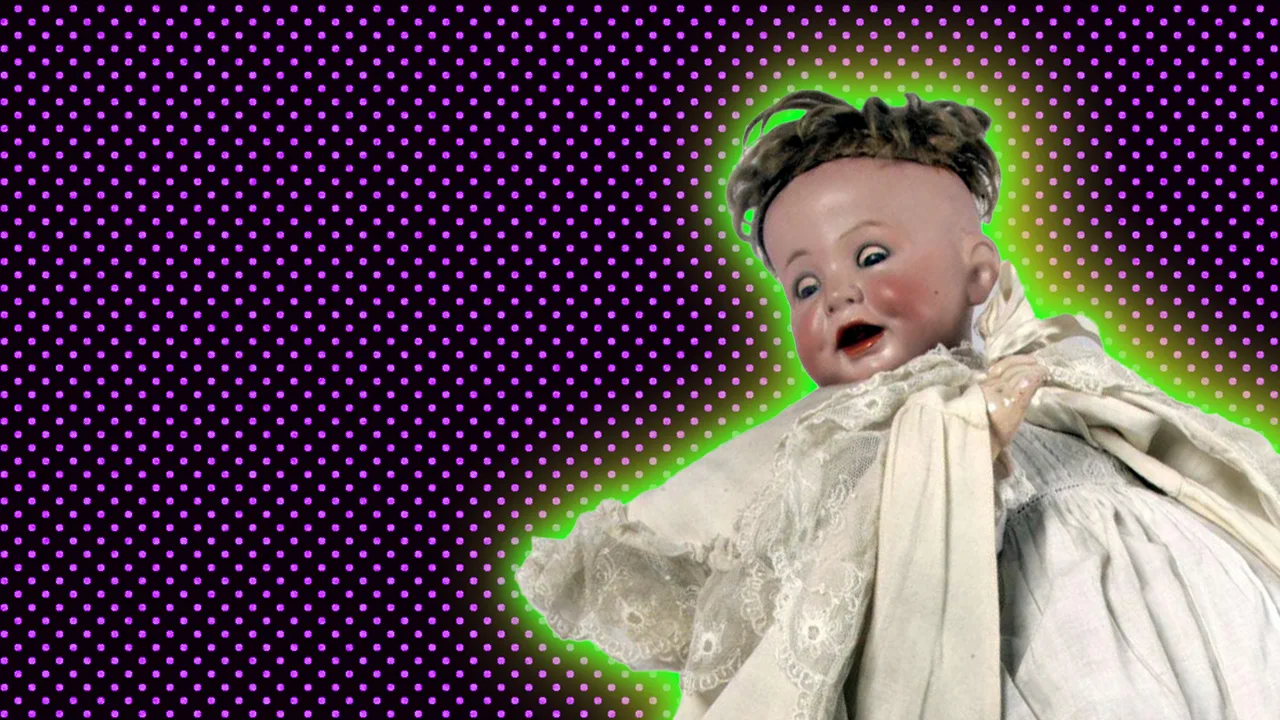A photo of an antique baby doll with a white dress on. It has dark hair and an open mouth and crying eyes. Set against a dark purple dotted background.