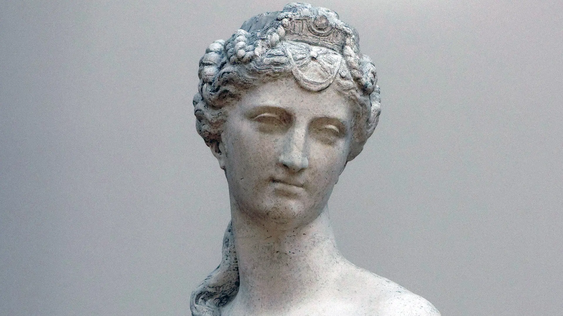 A photo of a the head and neck sculpture of Aphrodite the Goddess of Love with a grey background
