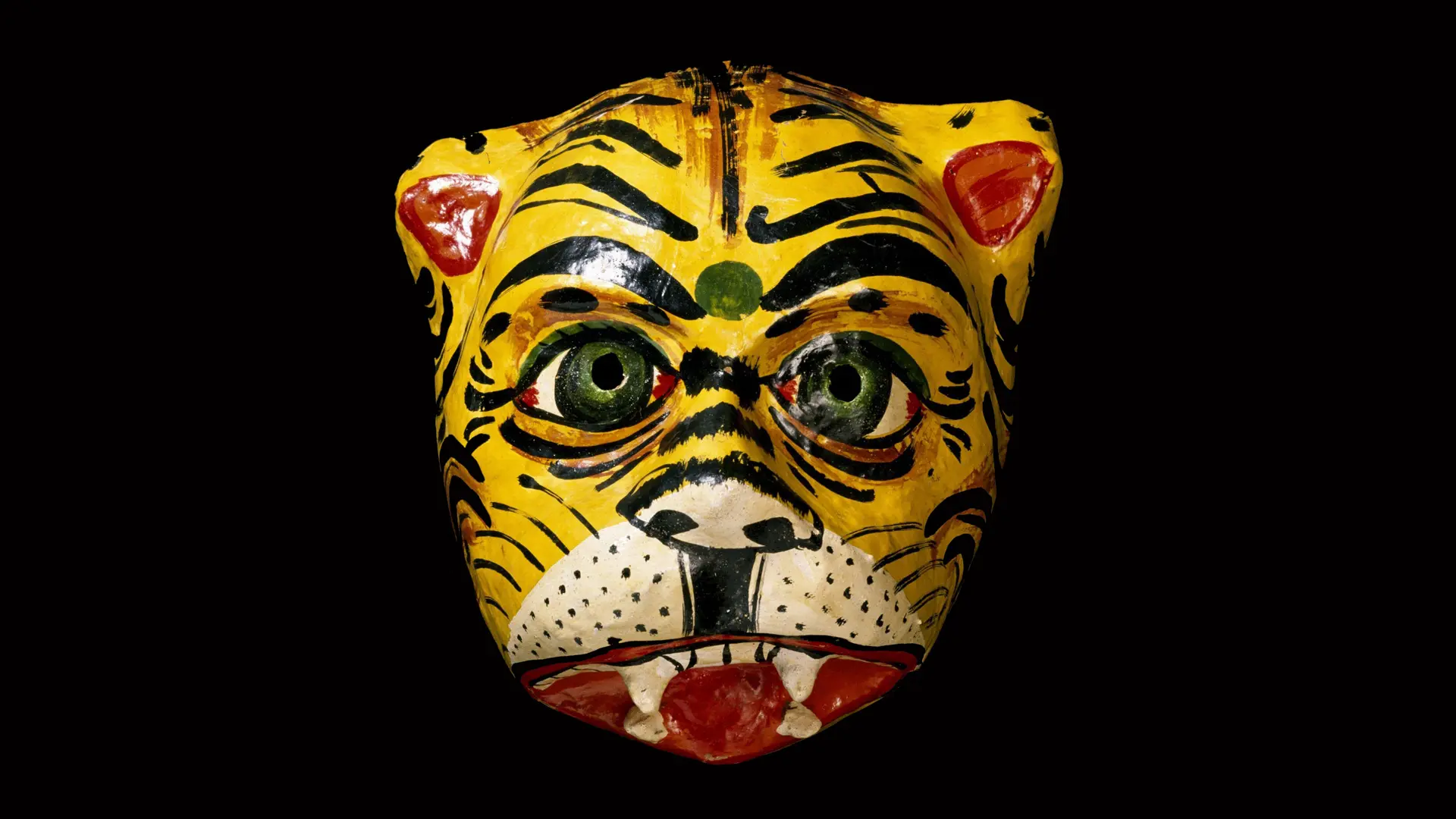 A photo of a tiger mask with an open mouth and teeth showing set against a black background.