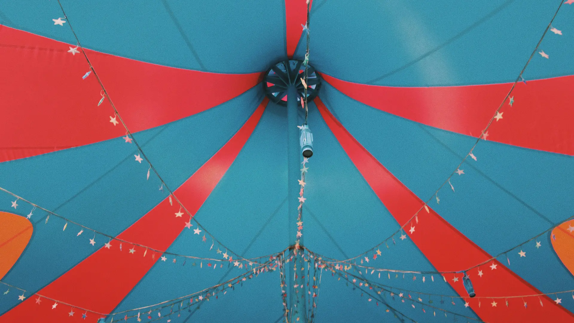 An inside view of a blue and red circus tent with festoon lighting.