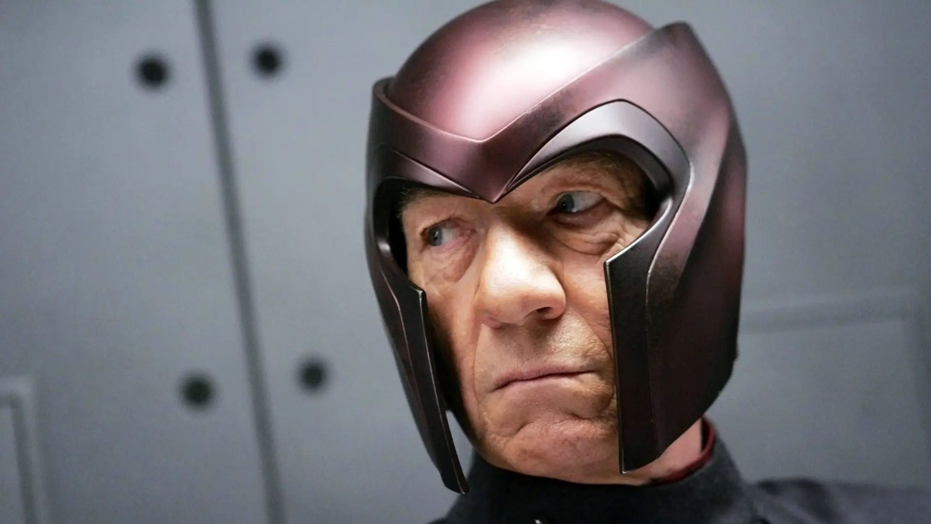 A still from Marvel's X-Men showing Magneto in his red helmet looking off to the side against a grey background.