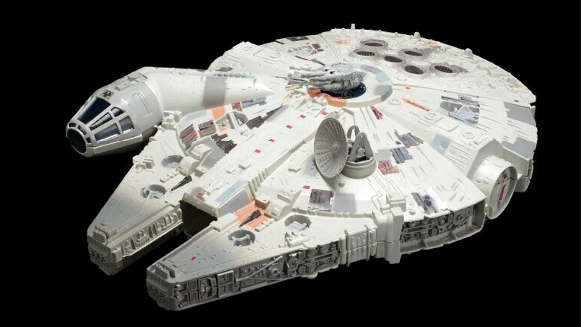 A photograph of a toy Millennium Falcon spaceship from Star Wars set against a black background.