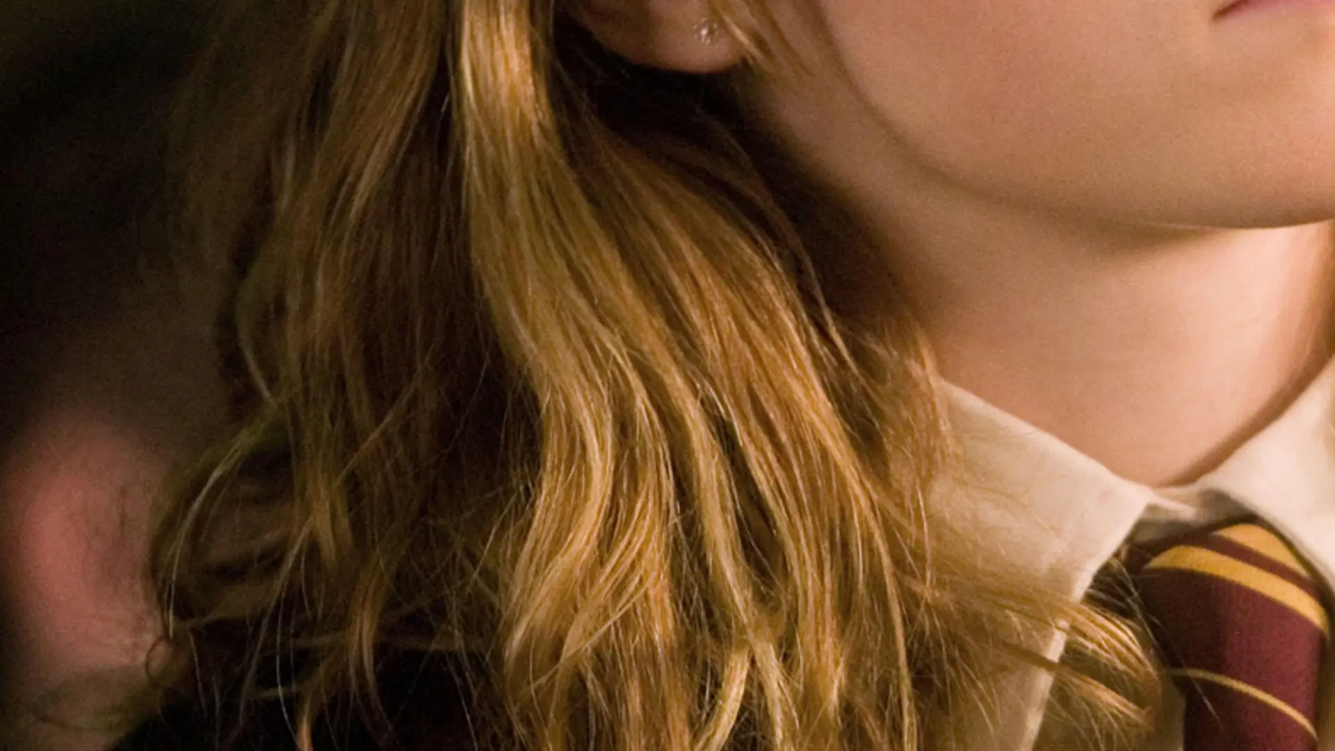 A close up of a girl with blonde hair and a shirt and red and yellow tie.
