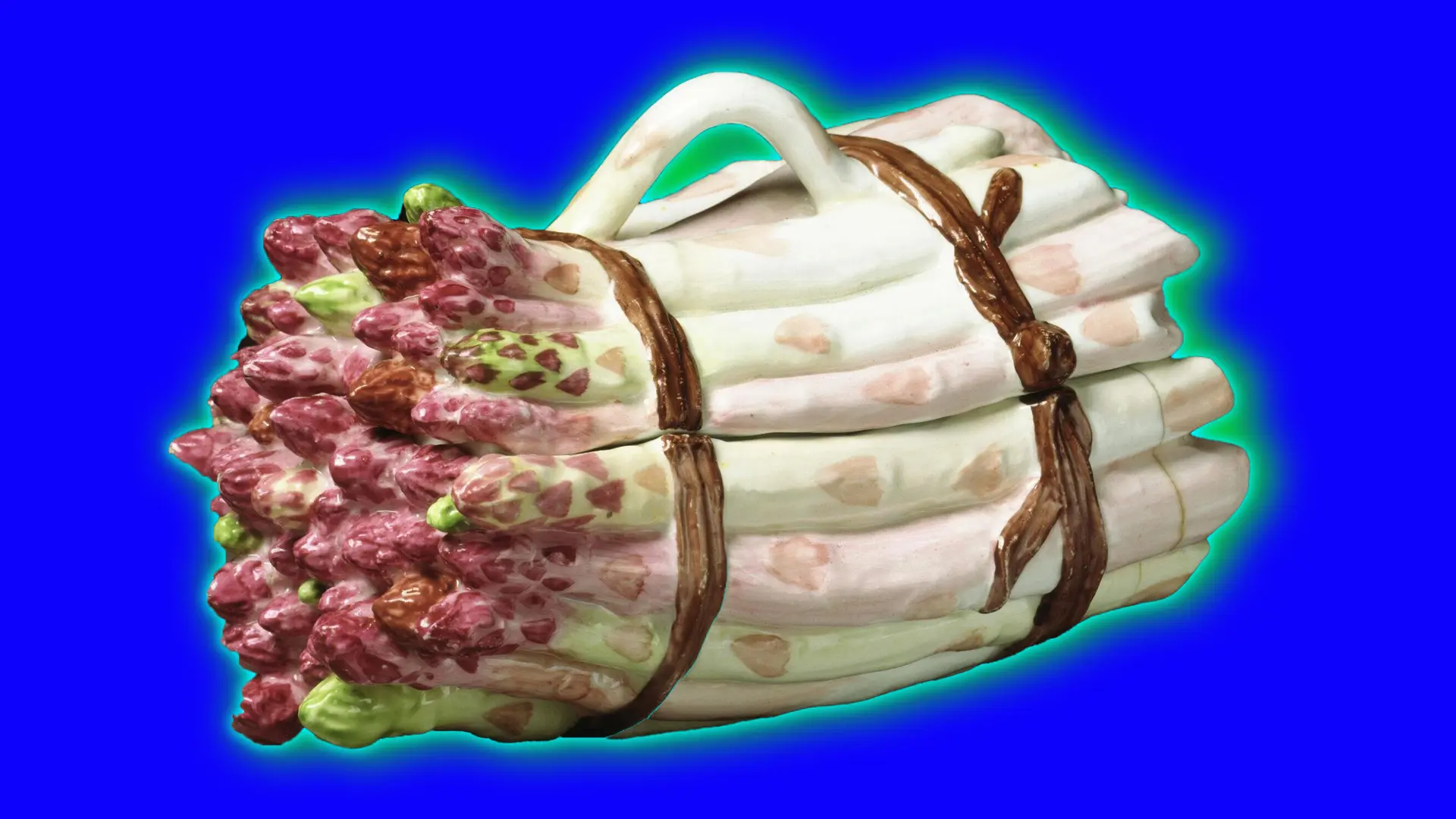 An image of a porcelain asparagus sculpture that also acts as a tureen. It is set against a royal blue background with a green halo.