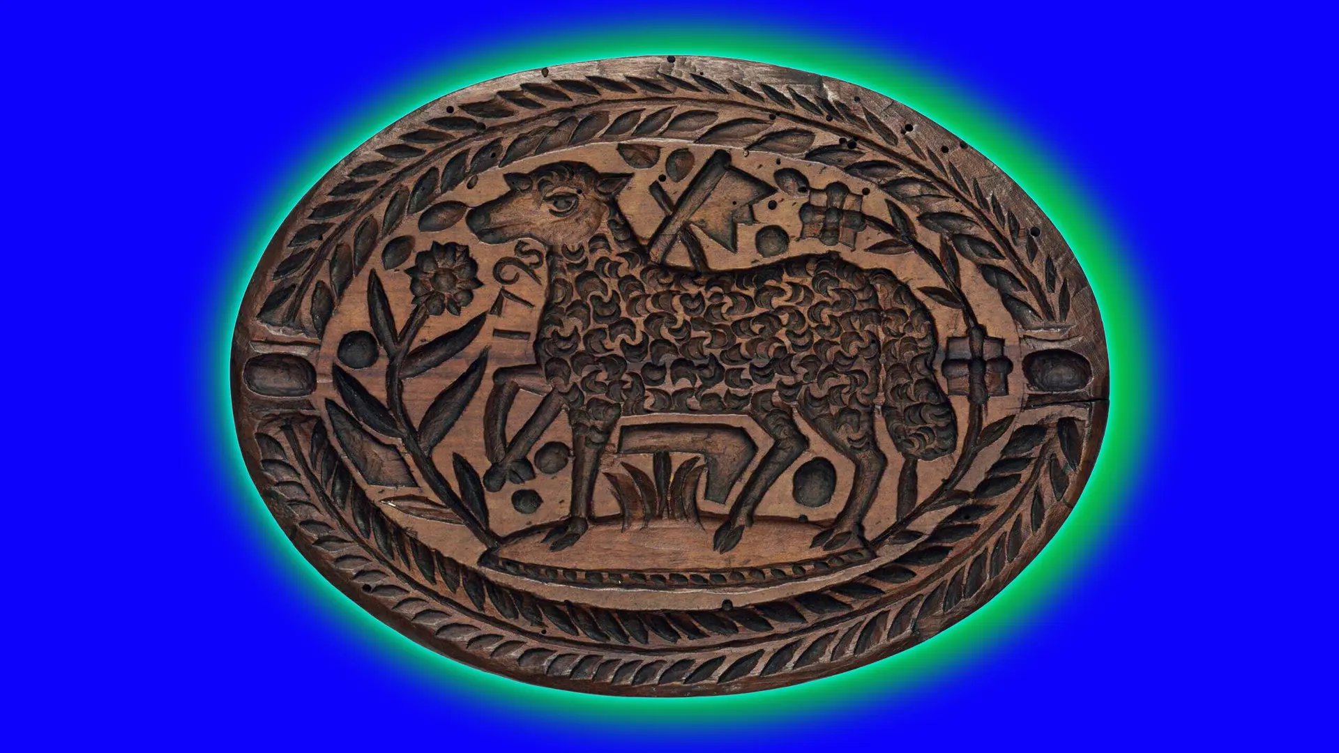 An image of a brown wooden stamp with a carving of a sheep and foliage around it in an oval shape set against a blue background with a green halo.