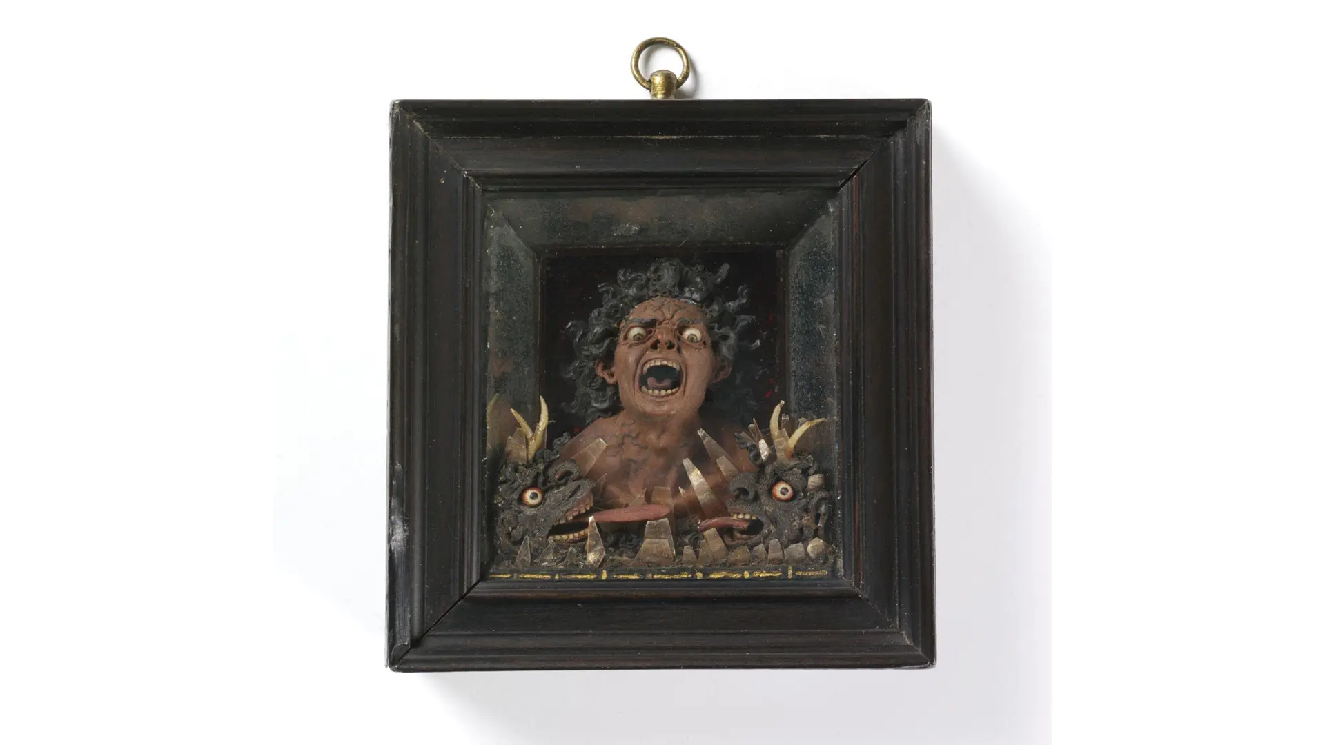 An image of a terrifying wax sculpture in a dark frame of a man screaming in eternal damnation with beasts and flames around him.