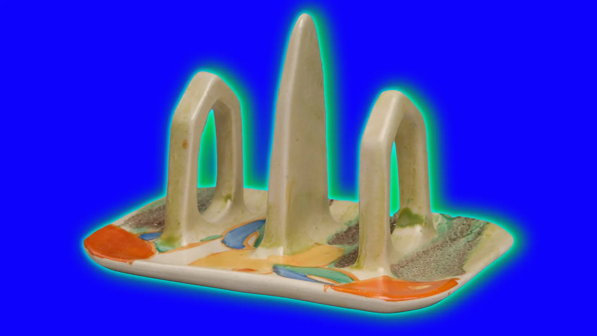 An image of a ceramic toast rack with a grey green colour and fruit painted on the base. It is set against a royal blue background with a green halo.