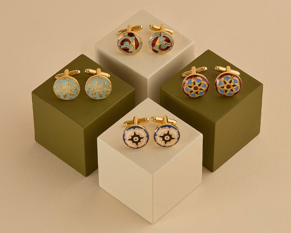 Three pairs of cufflinks propped up on plinths.