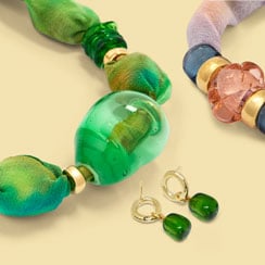 Close ups of a colourful necklace, a bracelet, and a pair of earrings, all made with blown glass.