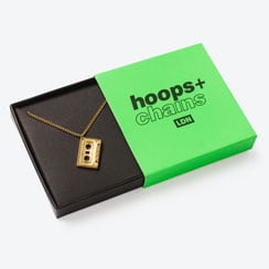 Gold cassette tape pendant necklace in a bright green gift box.